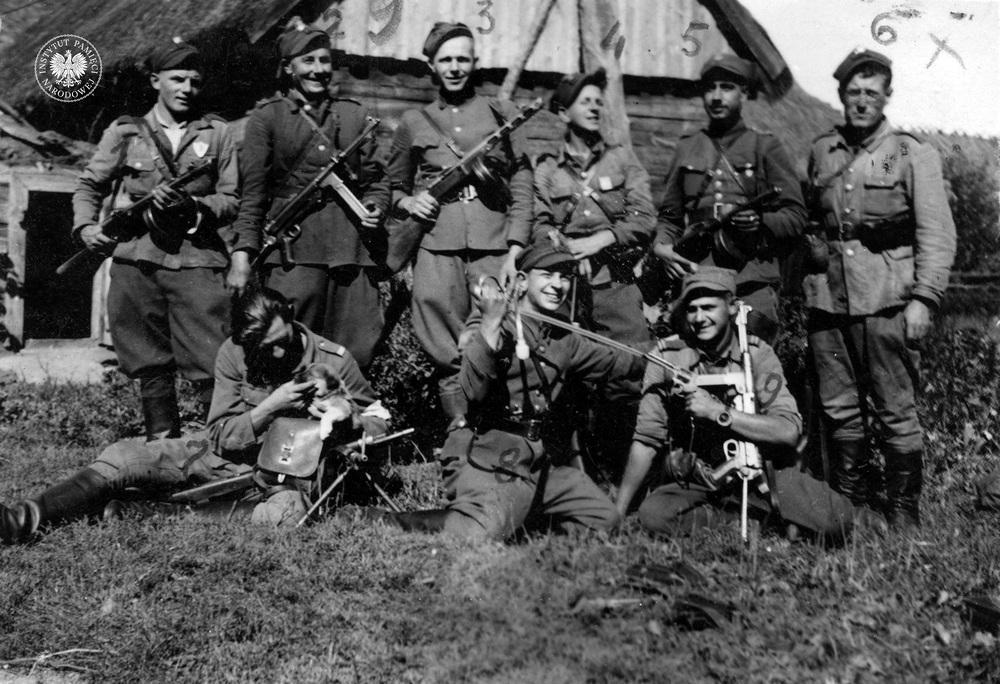 Członkowie V Brygady Wileńskiej AK na Białostocczyźnie. Od lewej stoją: Stanisław Wujec „Błyskawica” (nr 1), kpr. Michał Mieczkowski „Gryf” (nr 2), NN „Burnos” (nr 3), Jerzy Fijałkowski „Stylowy” (nr 4), kpr. Leon Krzemień „Murek” (nr 5), NN „Bąk” (nr 6). Na ziemi siedzą od lewej: kpr. podch. Antoni Roszczewski „Znicz” (nr 7), Zbigniew Fijałkowski „Pędzelek” (nr 8), kpr. Roman Wapierało „Dąbek” (nr 9), 1945 r. (IPN Bi 301/1)