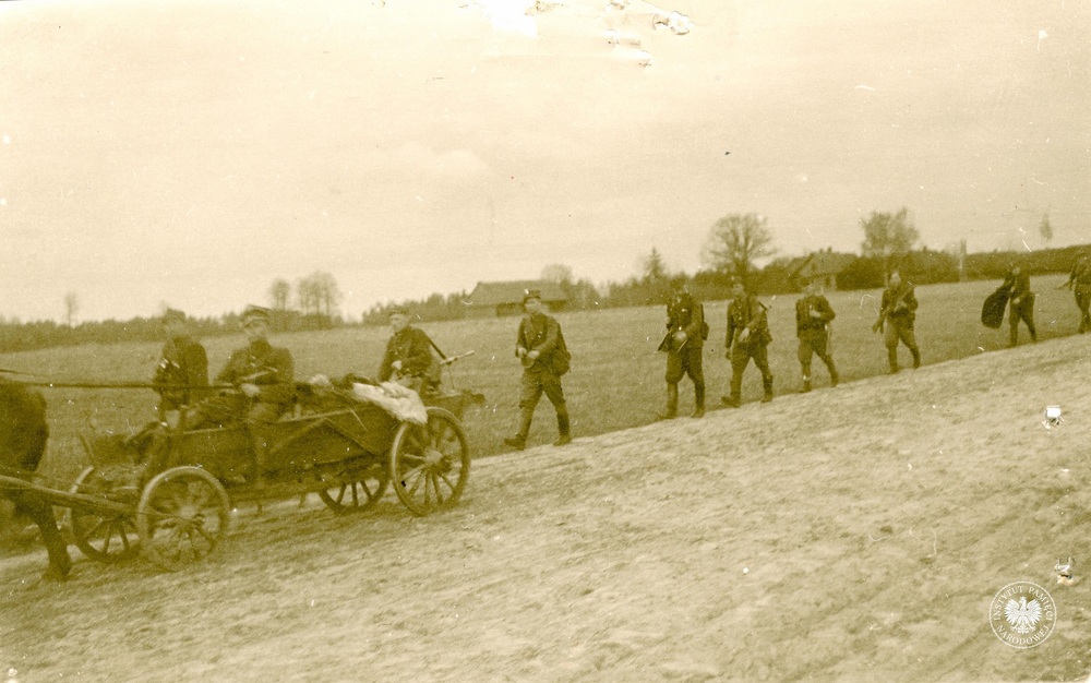 Członkowie V Brygady Wileńskiej AK podczas marszu. W tle zabudowania nieznanej miejscowości, kwiecień 1946 r. (IPN BU 024/97)
