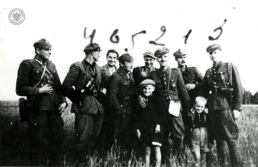 Grupa żołnierzy z oddziału partyzanckiego mjr. Hieronima Dekutowskiego „Zapora” z nieznanym mężczyzną i dwoma chłopcami na polu. Od lewej stoją: NN, kpt. Stanisław Łukasik „Ryś” (nr 4), Jerzy Stefański „Cedur” (nr 6), Aleksander Sochalski „Duch” (nr 5), NN, mjr Hieronim Dekutowski „Zapora” (nr 2), Jerzy Korcz „Bohun” (nr 1). Zbigniew Sochacki „Zbyszek” (nr 3), rok 1945 lub 1946 (IPN BU 525/4)