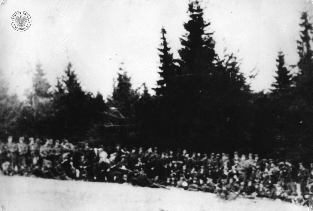 Zdjęcie członków oddziału partyzanckiego NSZ pod dowództwem Henryka Flame „Bartek”. Partyzanci stoją w kilku szeregach na tle lasu w Wiśle w dniu 3 maja 1946 r. Większość tych żołnierzy została zamordowana przez UB we wrześniu 1946 r. (IPN Ka 439/137)