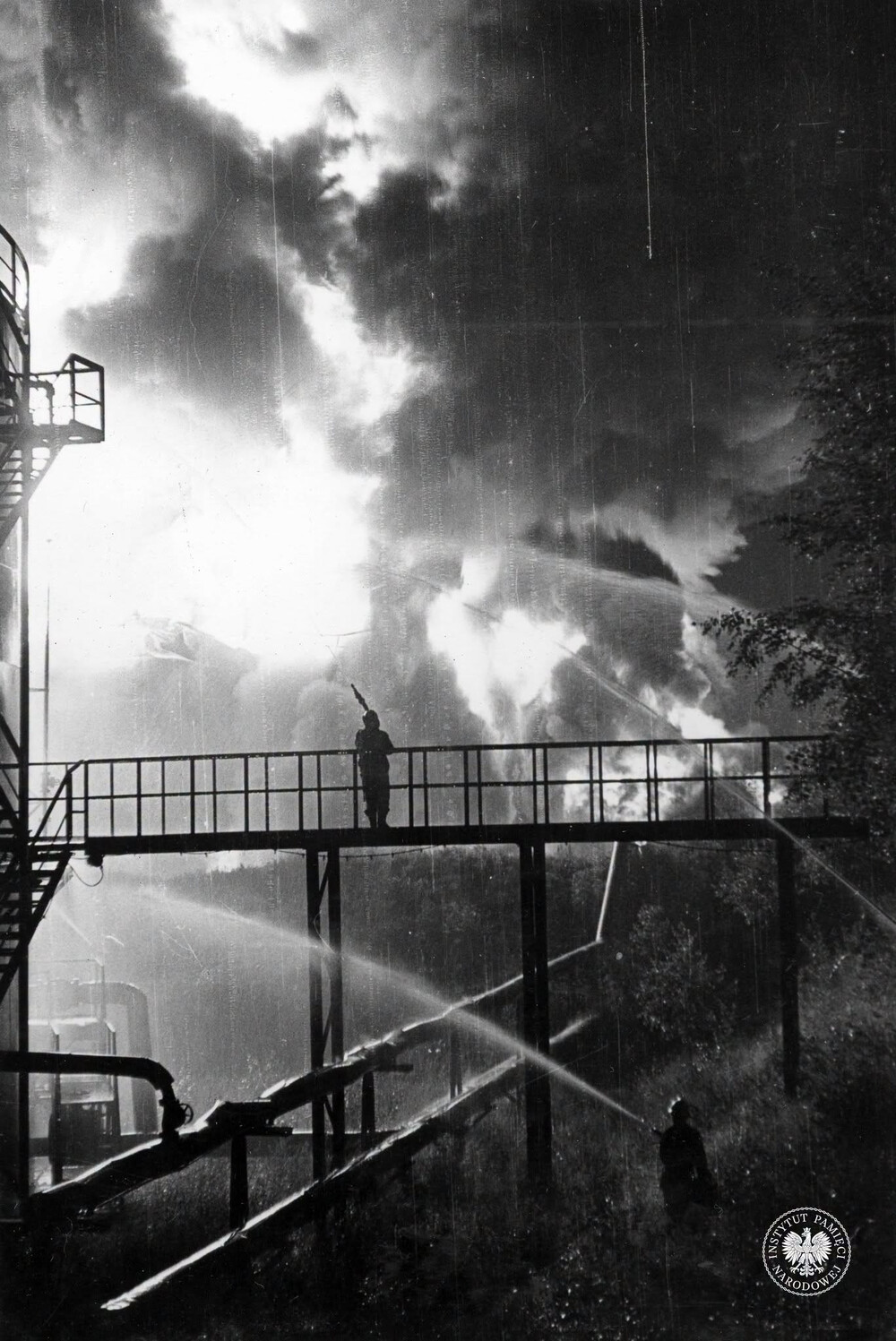 Strażacy gaszący pożar w rafinerii w jego pierwszej fazie, przed katastrofalnym wybuchem. Fotografię wykonano 26 VI 1971 r. między godziną 21 a 24 (IPN Ka 093/299)