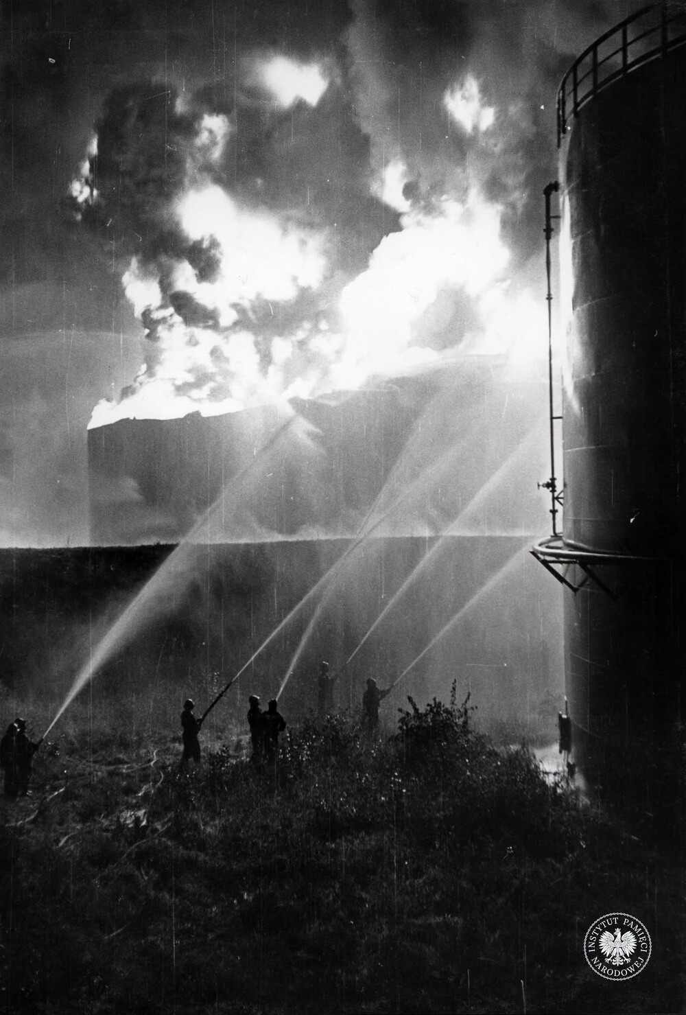 Strażacy gaszący pożar w rafinerii w jego pierwszej fazie, przed katastrofalnym wybuchem. Fotografię wykonano 26 VI 1971 r. między godziną 21 a 24 (IPN Ka 093/299)