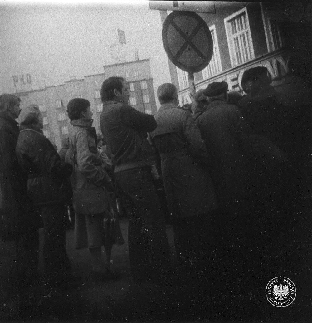 Przykładowa fotografia operacyjna, wykonana z ukrycia podczas obserwacji. Grupa osób stoi na Rynku w Katowicach, blisko ul. Teatralnej. Zdjęcie zrobiono w październiku 1981 r. (IPN Ka 435/3)