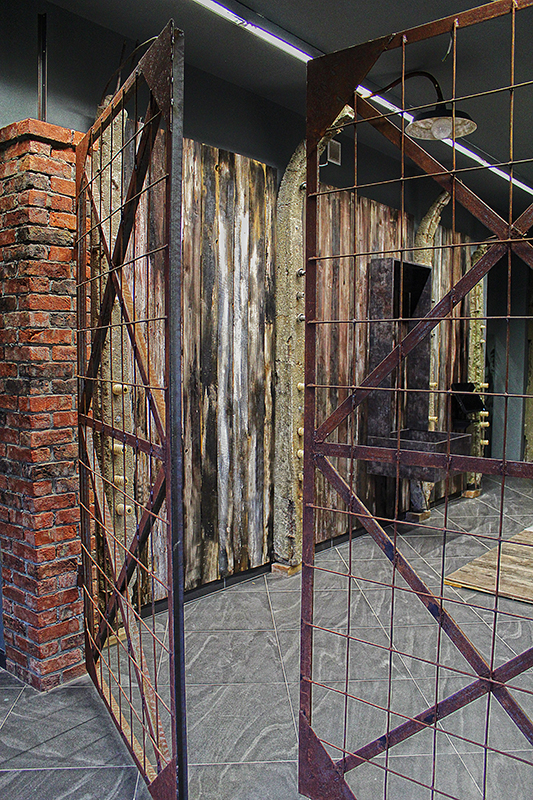 Rekonstrukacja bramy wewnętrznej obozu, w tle oryginalny betonowy słup ogrodzenia z izolatorami i drutem kolczastym